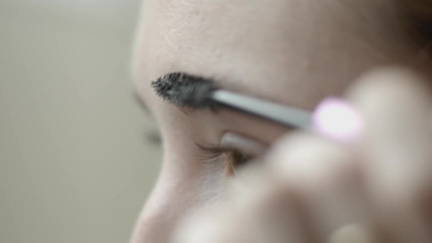 A woman is brushing her eyebrows