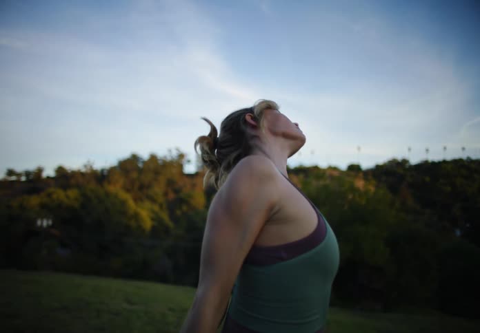 Portrait of a woman in an open field exercising and stretching her body