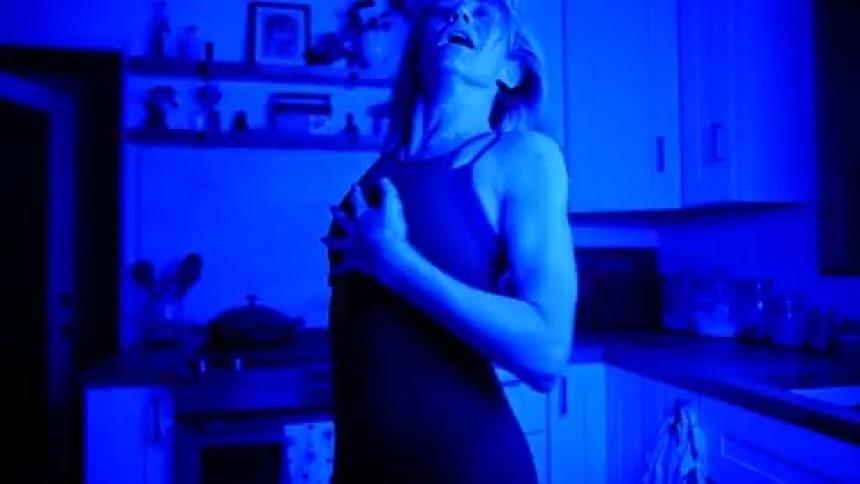 Portrait of a woman in the kitchen dancing with blue lights turning on and off