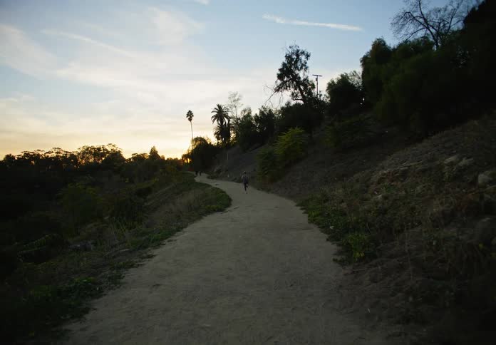 Woman running backwards in a natural environment wearing fitness clothes