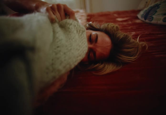 A crying woman lying in bed with a piece of clothing in her hands