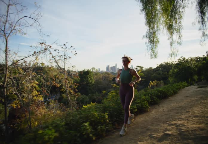 Woman running up a hill and slowing down very slowly
