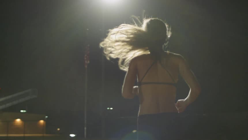 Woman runs in a stadium in the middle of the night