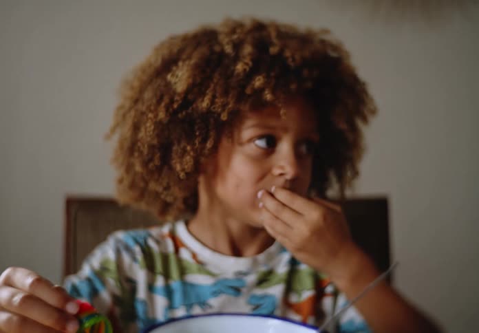 Boy sitting at the table eating cereal with a spoon