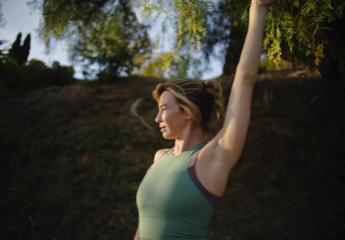 A woman stretches and touches the tree branch