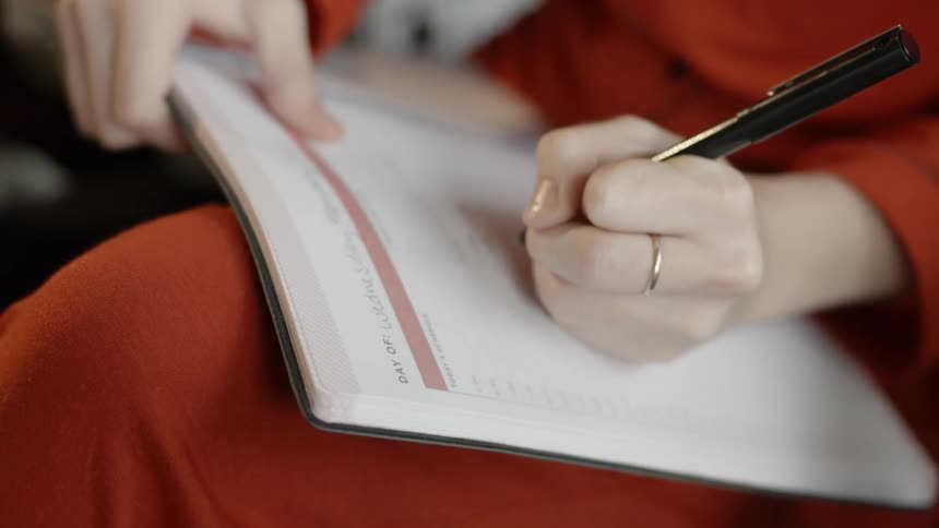 A woman is writing in a planner