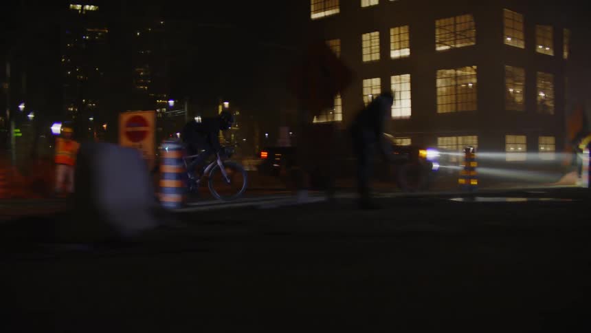 A person riding a bicycle at high speed on a potholed city street