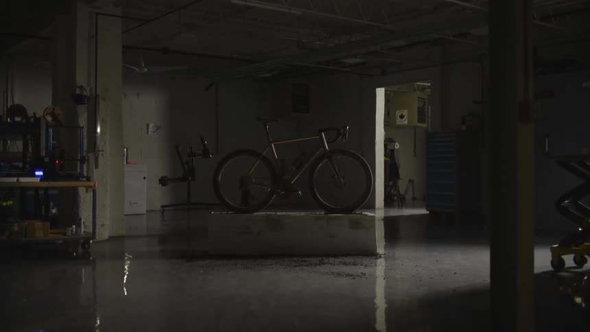 A bicycle is stopped on top of an object in an interior with a dirty reflective floor