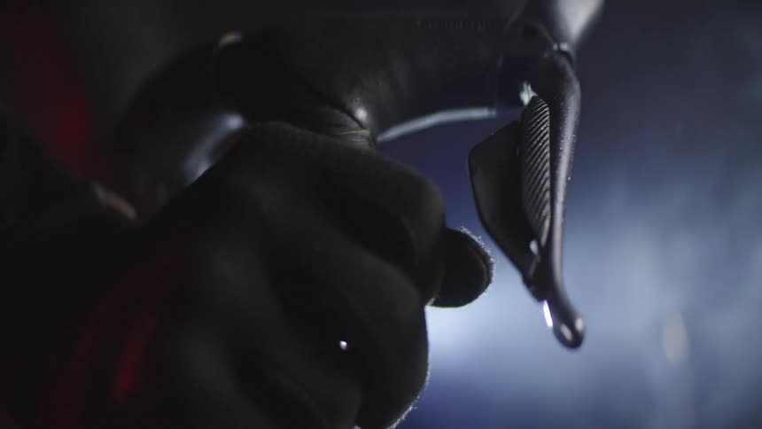 Closeup of a mans hand gripping the handlebar of a moving bicycle at night