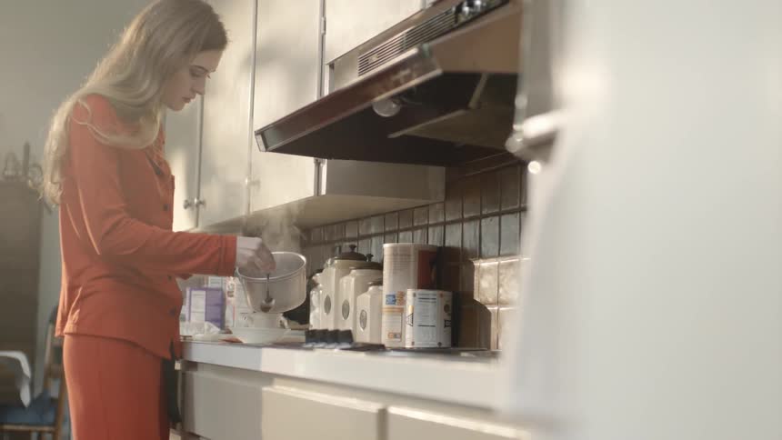 A woman pours steaming water into a tea cup