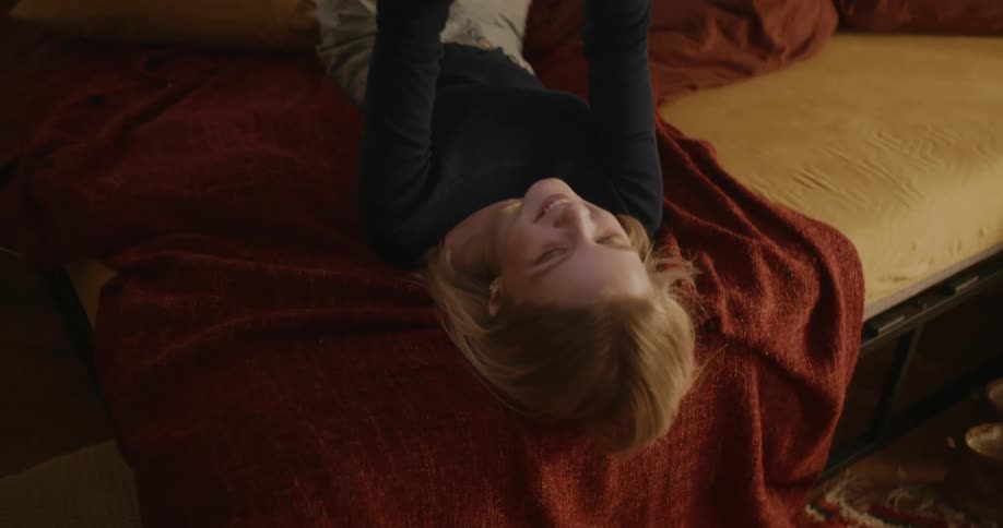 A girl lying in bed talking via text message on her cell phone