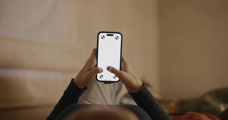 Someone lying down scrolling on an all white smart phone screen