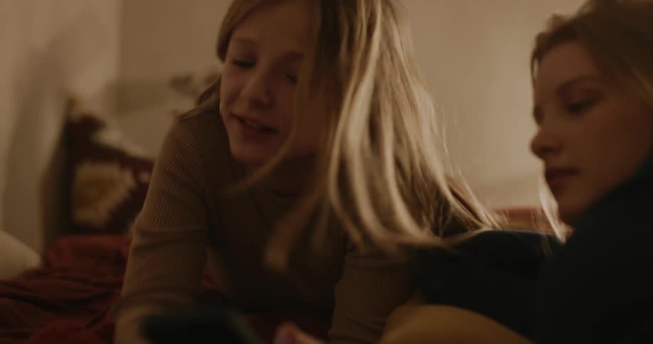 Two teenagers talk while looking at a cell phone