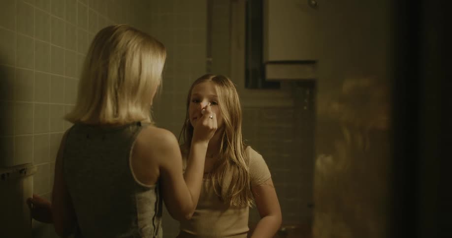 Young woman applying makeup to a teenager in the bathroom