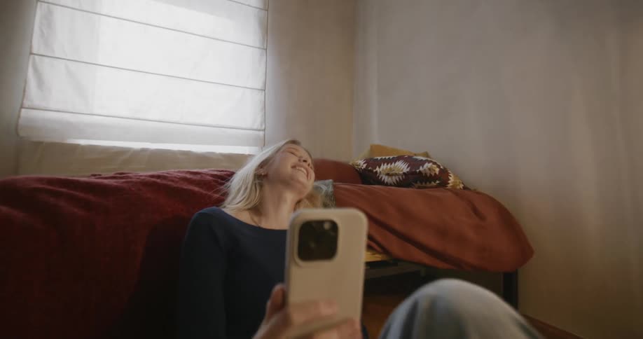 A woman sitting on the floor of her room talking on her cell phone