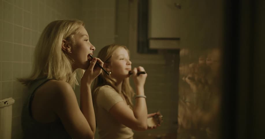 Young woman and a teenager in the bathroom smiling putting on makeup