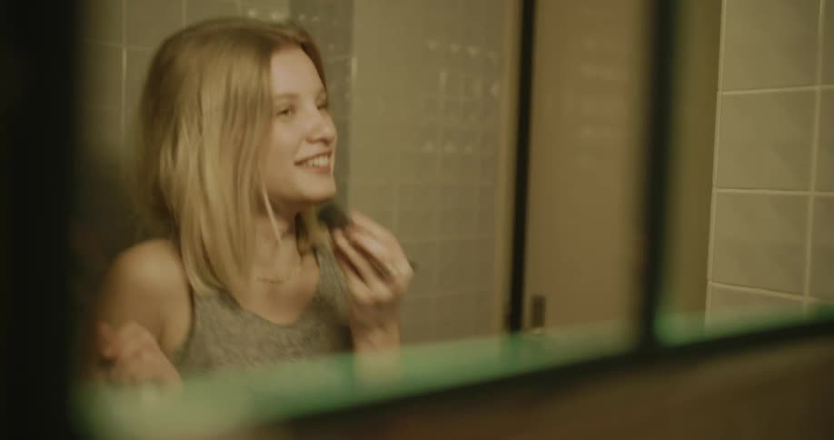 Portrait of two teenage girls in the bathroom in front of the mirror dancing and putting on makeup