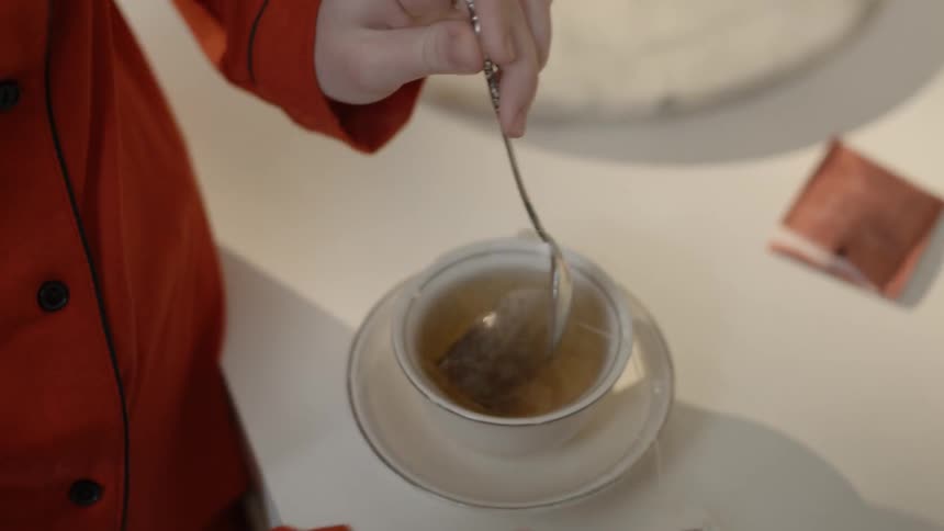 A person stirs a tea bag in a cup of water