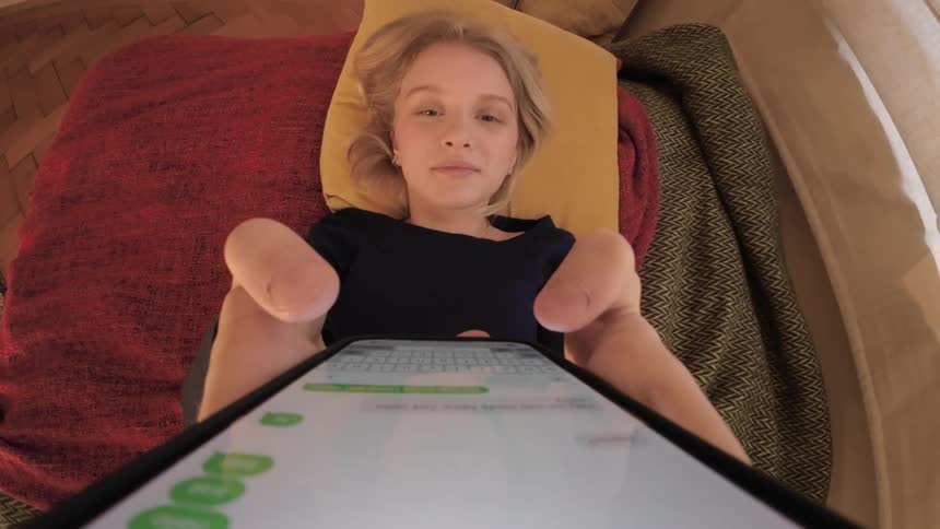 girl on bed picking up her phone