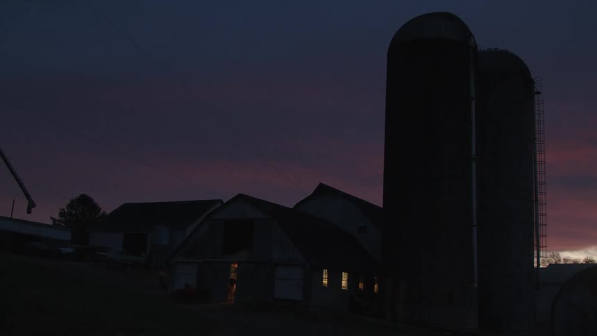 Silhouette of a residence in a rural area with two storage tubes next to it on a purple sky day