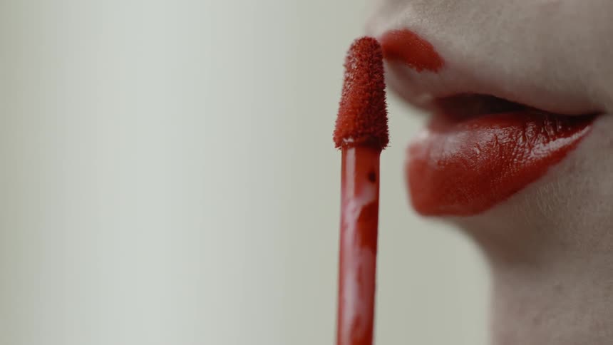 A woman is applying lipstick