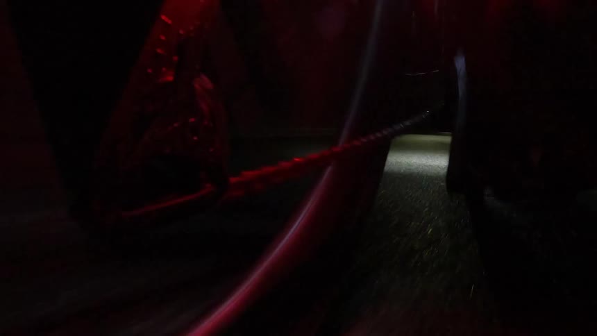 Close up of the wheels of a bicycle riding on a road at night