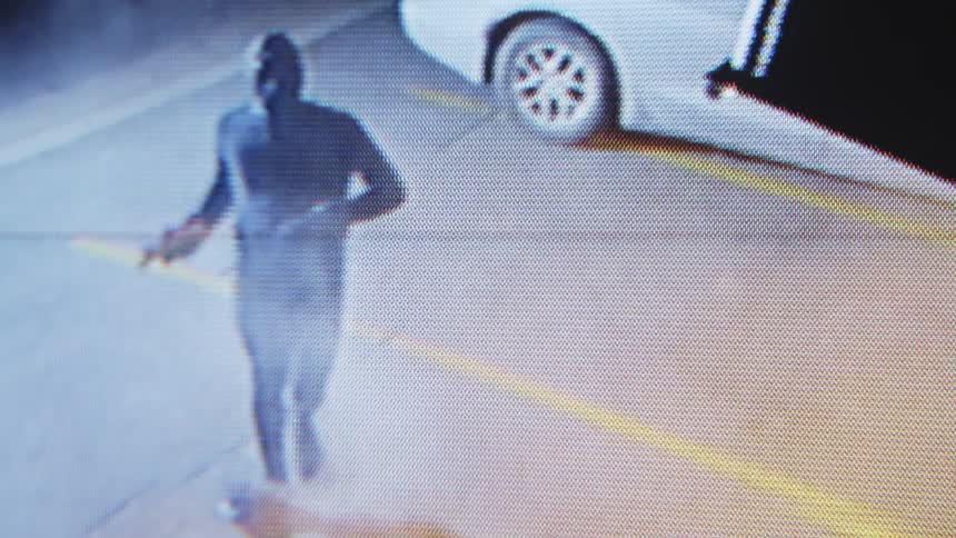 Camera video of a hooded man judging an object in an establishment at night