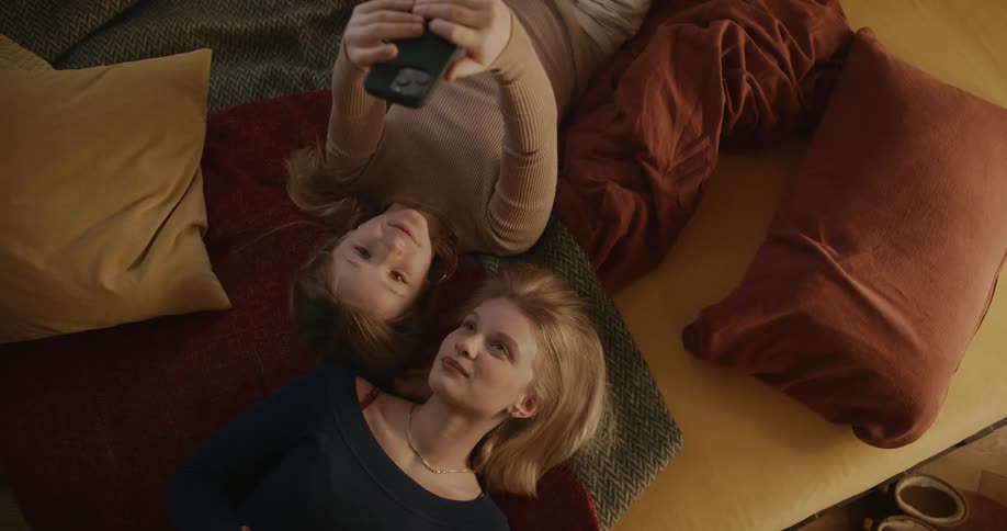 Portrait of a young woman and a little girl lying in bed and taking a selfie