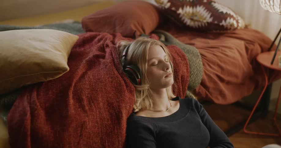 A girl sitting in her room listening to music on headphones