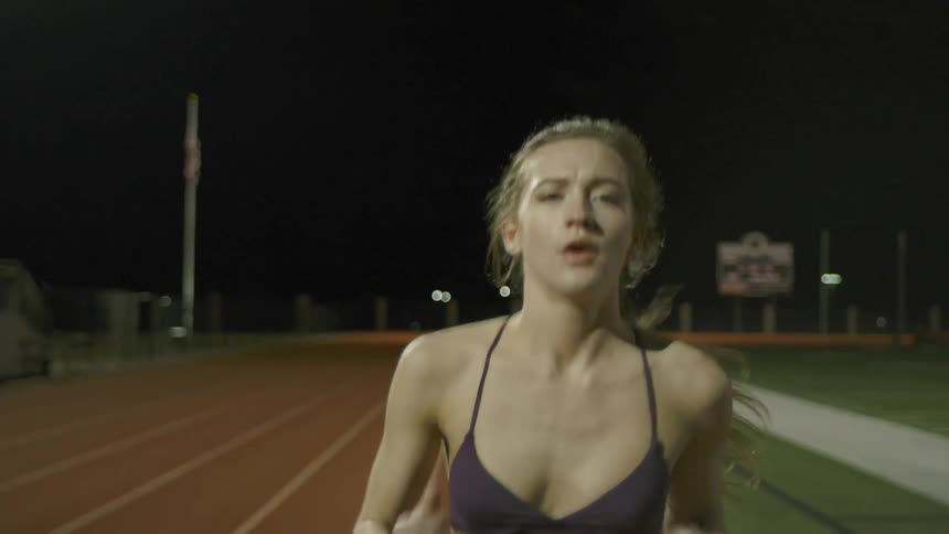 A woman runs on a running track