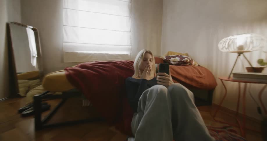A woman blows a kiss to her cell phone