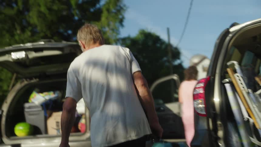 A man puts a cooler into a car