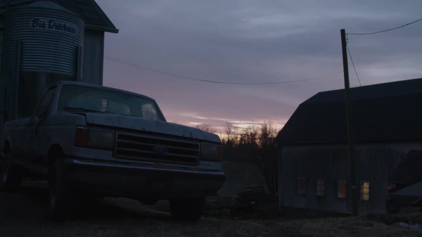 Silver pickup truck parked in front of a farm house