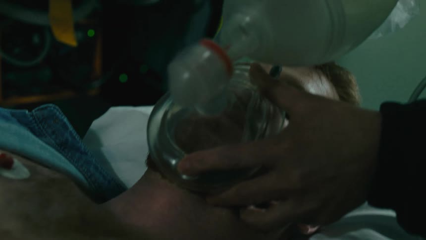 A medical professional uses an oxygen mask on a patient