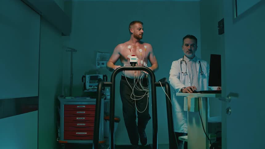 Man running on a treadmill and being monitored by equipment and a doctor