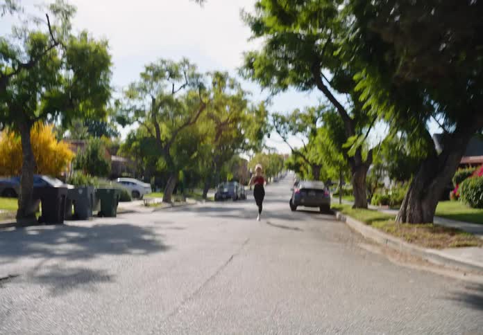 A white woman runs and jumps on a suburban street