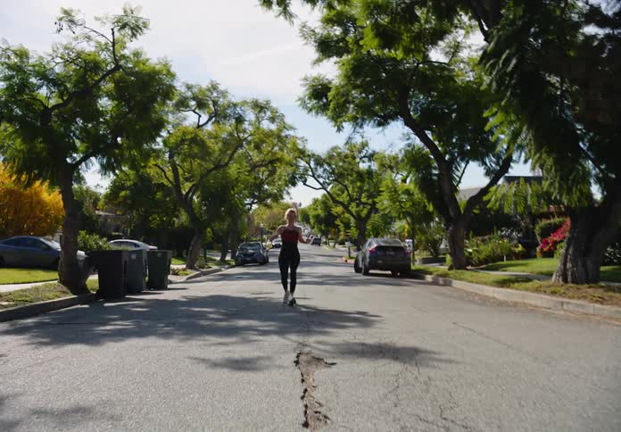 Woman running down a street in a residential neighborhood and jumping for joy