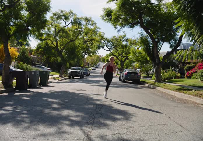 A woman exercising on her neighborhood street on a sunny day