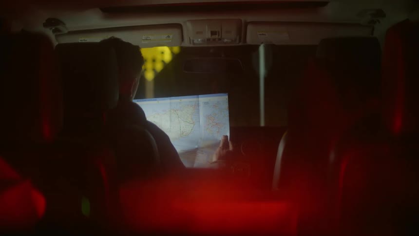 Car view of a driver looking at a map as a speeding bicycle passes in front of him