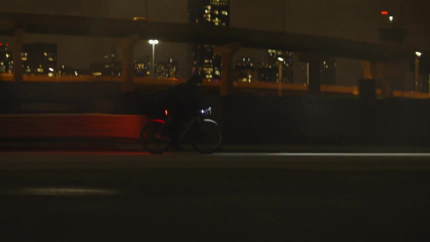 A man rides a bicycle down a city street in foggy conditions