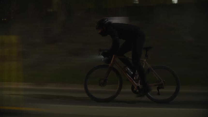 Cyclist pedaling at high speed through the city streets at night