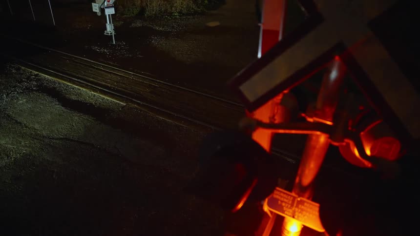 A person running a bicycle across a railway crossing at night