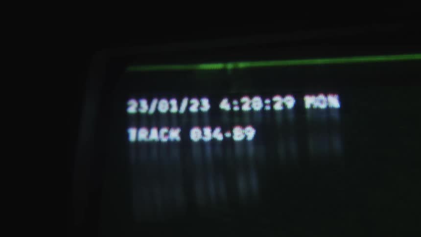 Closeup on a screen playing a camera video of a silhouette of a person passing by on a bicycle at night