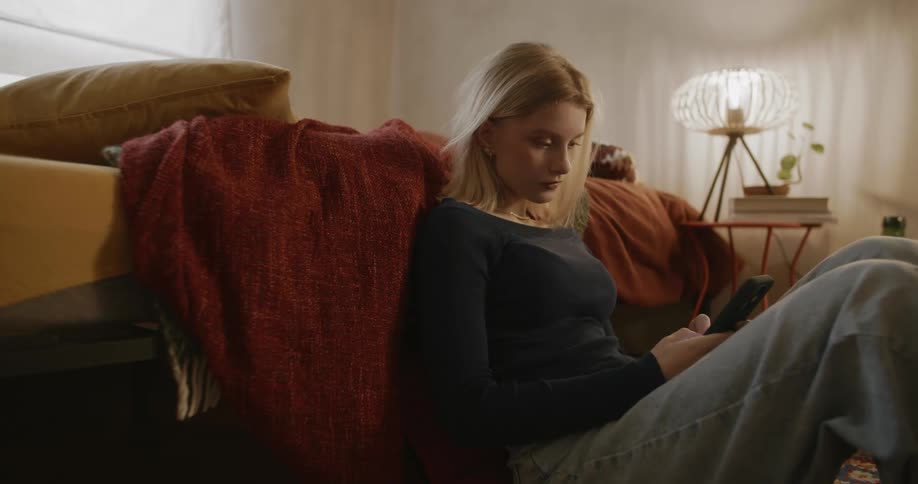 A girl is using her cell phone in her bedroom