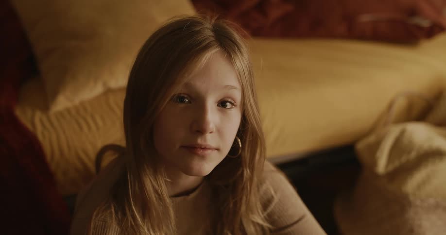 Closeup of the face of a young teenager sitting on the living room floor