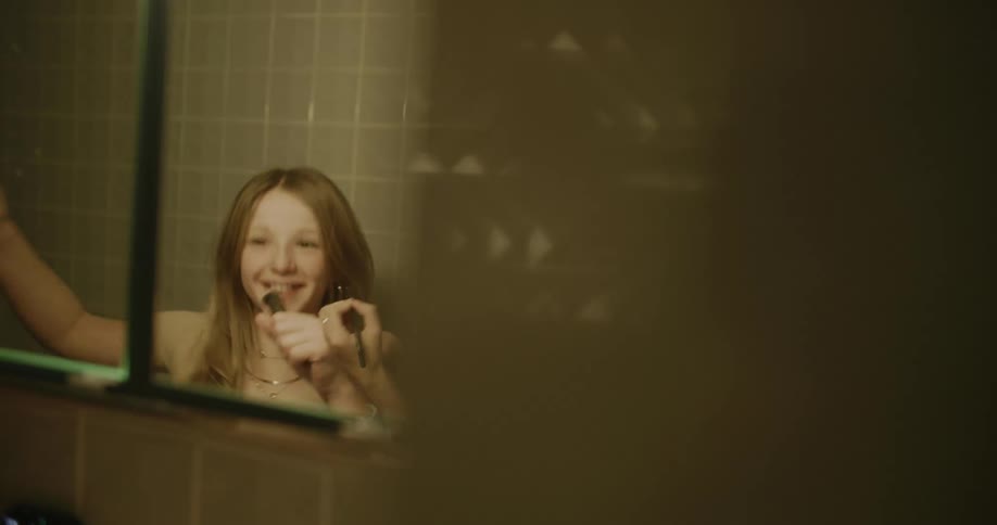 A girl dances while having makeup applied