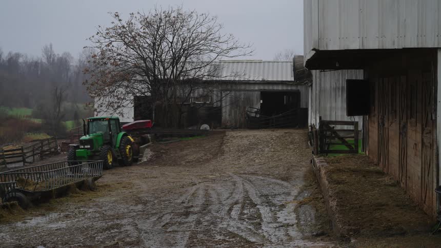 View of a tractor in the midst of a ranch on a rainy day