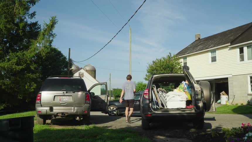 A man walking between two cars parked in front of a house