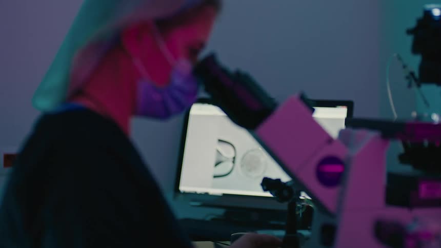 A doctor is looking through a microscope