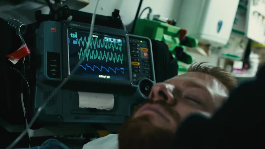 A persons hand placing braces on the chest of a patient who is sleeping on a stretcher